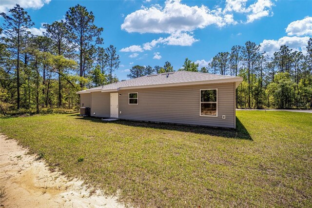 view of side of property with a yard and central AC