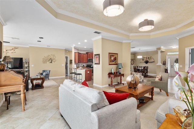 tiled living room with ornamental molding and a tray ceiling