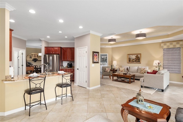 kitchen featuring a kitchen bar, kitchen peninsula, stainless steel fridge, and ornamental molding