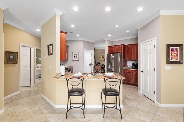 kitchen with sink, stainless steel fridge, ornamental molding, a kitchen bar, and kitchen peninsula