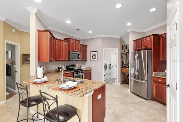 kitchen featuring a kitchen breakfast bar, separate washer and dryer, stainless steel appliances, and ornamental molding