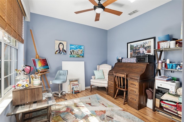 office with light wood-type flooring and ceiling fan