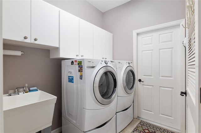 clothes washing area with washer and clothes dryer, sink, and cabinets