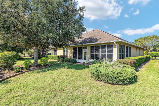 back of house featuring a sunroom and a lawn