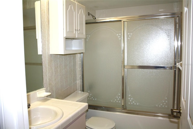 full bathroom featuring toilet, vanity, and combined bath / shower with glass door