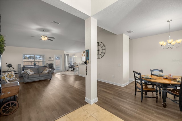 dining room with hardwood / wood-style floors, ceiling fan with notable chandelier, and a textured ceiling