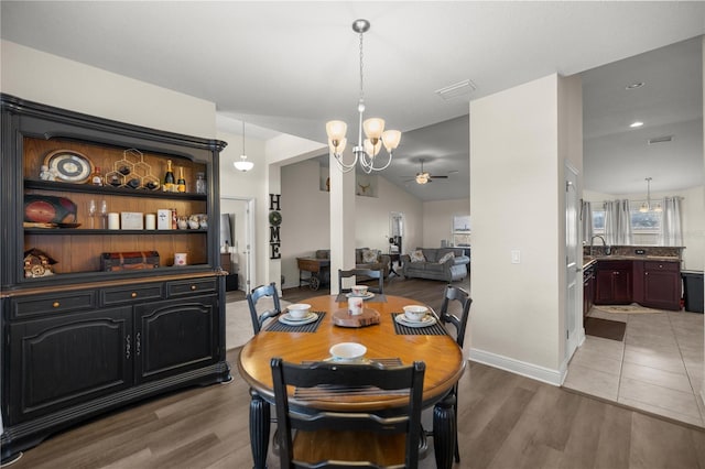 dining space with hardwood / wood-style floors, ceiling fan with notable chandelier, and sink