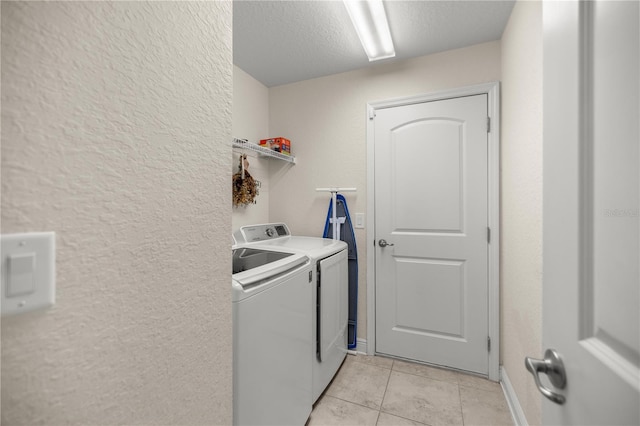 laundry area featuring a textured ceiling, washer and clothes dryer, and light tile patterned flooring