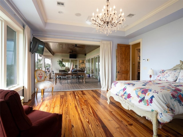 bedroom featuring hardwood / wood-style flooring, a notable chandelier, a raised ceiling, and crown molding