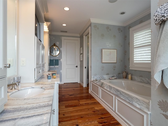 bathroom featuring hardwood / wood-style floors, a washtub, ornamental molding, and vanity