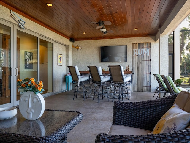 view of patio with ceiling fan and a bar