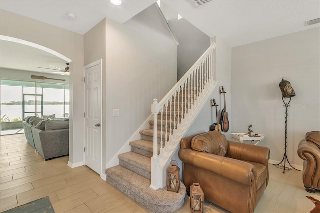 staircase with visible vents, baseboards, a ceiling fan, and wood finished floors