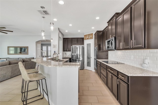 kitchen with visible vents, arched walkways, stainless steel appliances, dark brown cabinets, and open floor plan