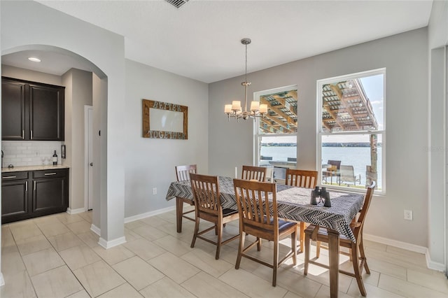 dining area with baseboards, plenty of natural light, and arched walkways