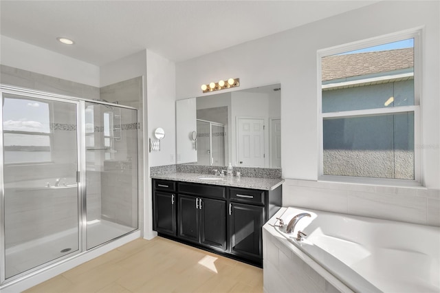 full bathroom featuring a stall shower, vanity, and a bath