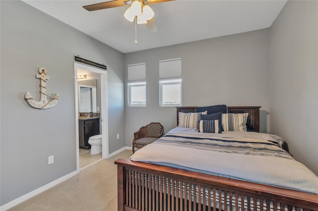 bedroom featuring baseboards, light carpet, a ceiling fan, and ensuite bathroom