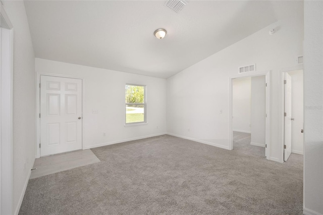 empty room featuring light carpet and vaulted ceiling