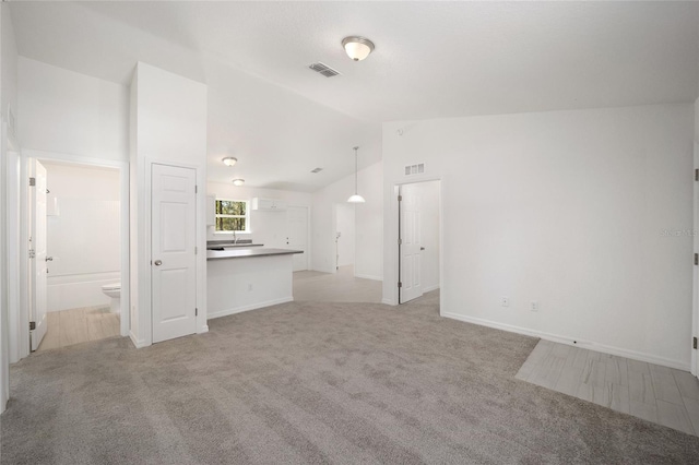 unfurnished living room with light carpet and high vaulted ceiling