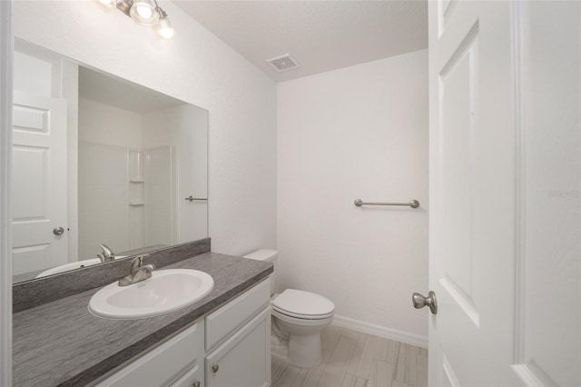 bathroom with a textured ceiling, vanity, toilet, and a shower