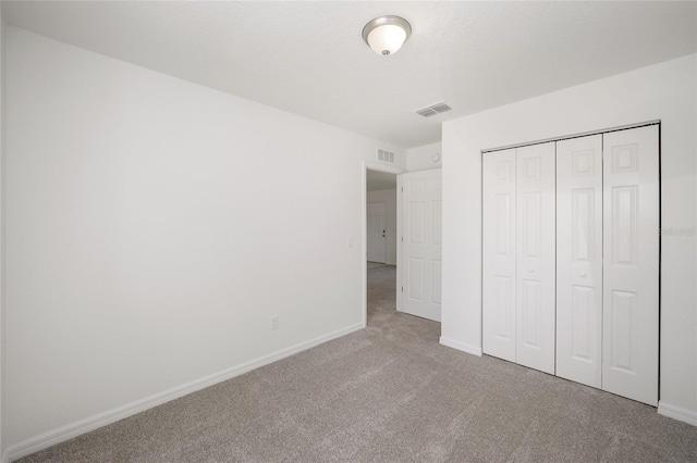 unfurnished bedroom with light carpet and a closet