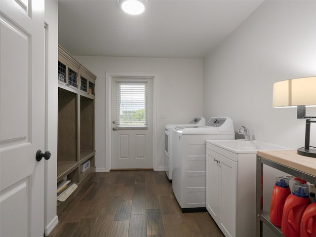 clothes washing area with washer and clothes dryer, cabinets, and dark wood-type flooring