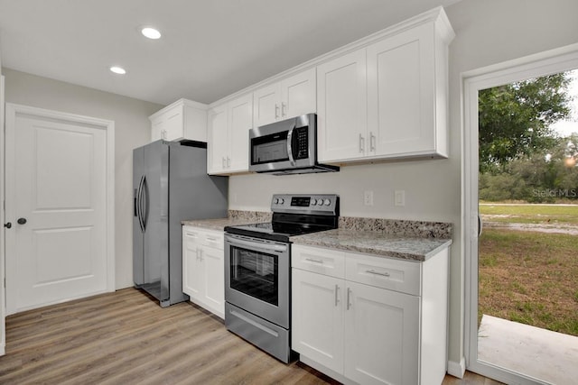 kitchen featuring white cabinetry, light hardwood / wood-style floors, light stone counters, and appliances with stainless steel finishes