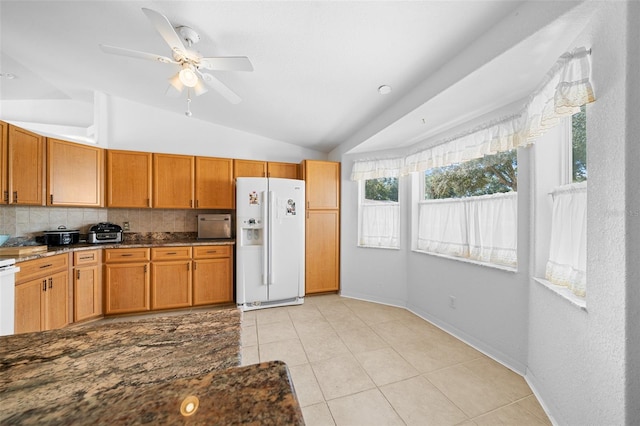 kitchen with lofted ceiling, backsplash, ceiling fan, white fridge with ice dispenser, and light tile patterned floors