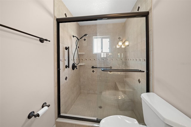 bathroom featuring toilet and a shower with door