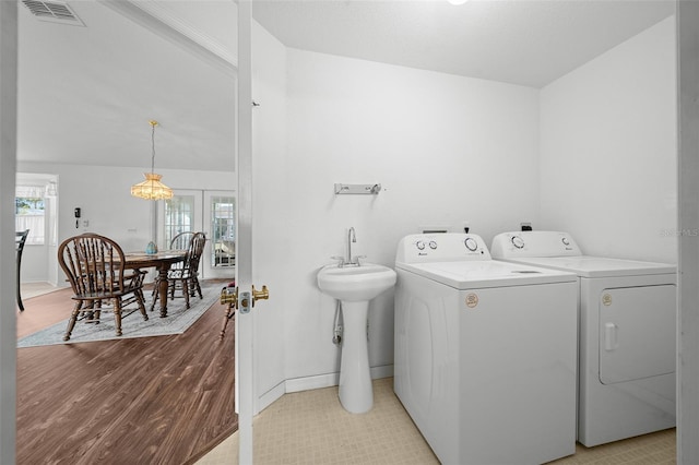 washroom with washer and clothes dryer, light hardwood / wood-style floors, sink, and a wealth of natural light