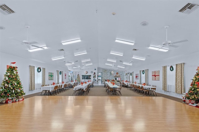 gym with hardwood / wood-style flooring, ceiling fan, and vaulted ceiling