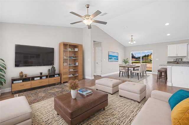 living room featuring ceiling fan with notable chandelier, light wood-type flooring, and high vaulted ceiling