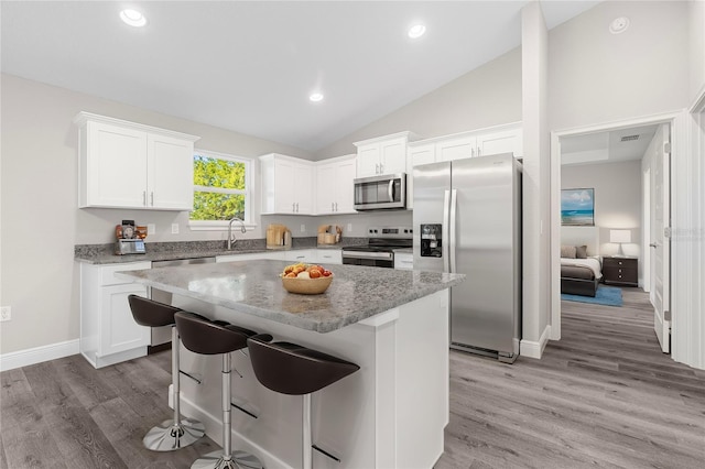 kitchen with a center island, white cabinetry, stainless steel appliances, and a breakfast bar area