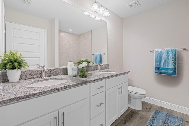 bathroom featuring tiled shower, vanity, hardwood / wood-style flooring, and toilet