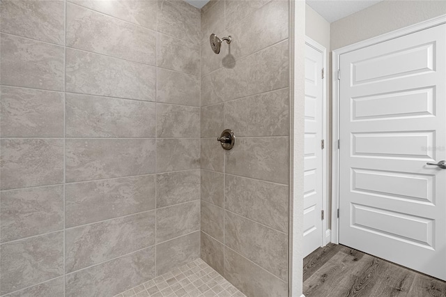 bathroom with wood-type flooring and tiled shower