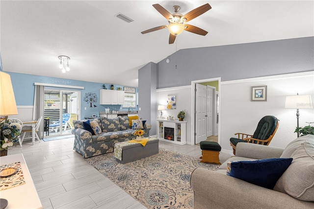 living room featuring ceiling fan, light hardwood / wood-style floors, and vaulted ceiling