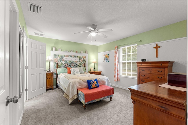 carpeted bedroom featuring ceiling fan and a textured ceiling