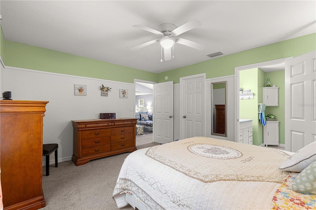 bedroom with light colored carpet, ensuite bath, and ceiling fan