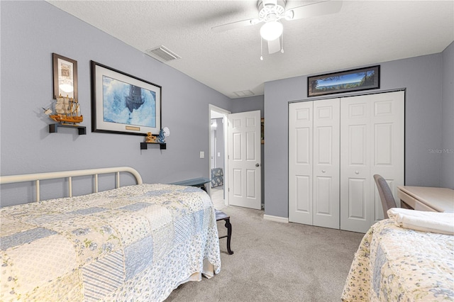 bedroom featuring ceiling fan, a closet, light carpet, and a textured ceiling