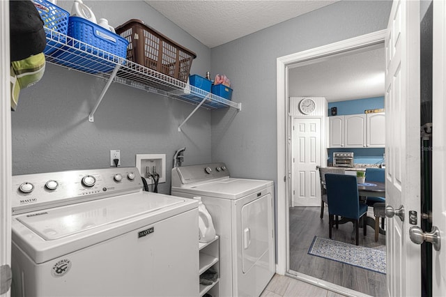 clothes washing area with washing machine and clothes dryer, light hardwood / wood-style flooring, and a textured ceiling