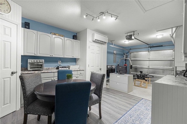 interior space featuring white cabinetry, light countertops, a textured ceiling, and a wall mounted AC