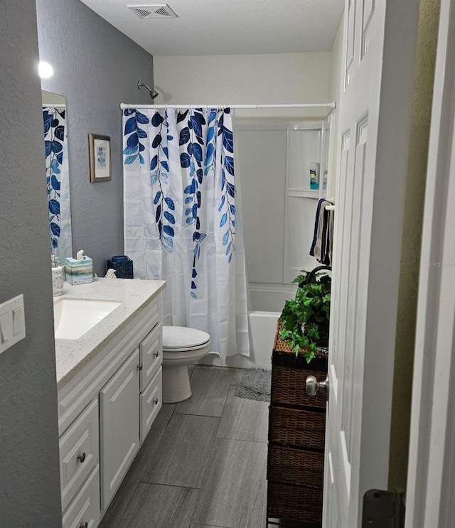 bathroom featuring shower / bath combo, visible vents, a textured wall, toilet, and vanity