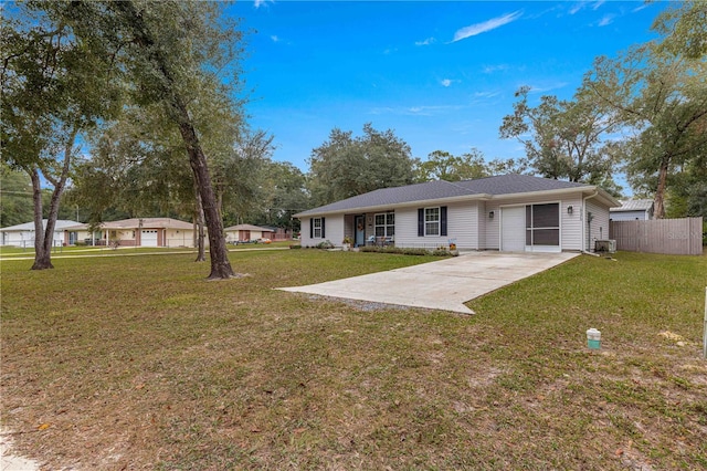 rear view of house with an attached garage, central AC, fence, concrete driveway, and a lawn