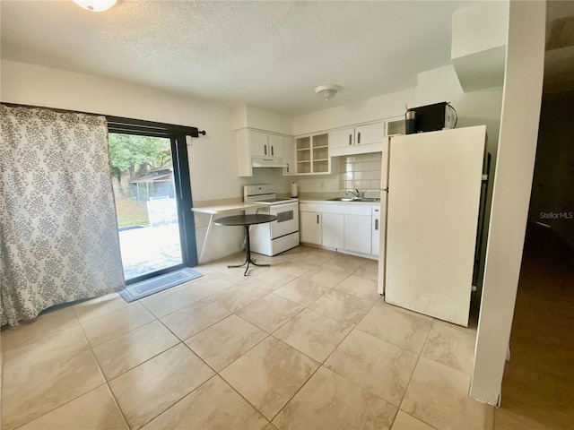 kitchen featuring white appliances, white cabinets, sink, light tile patterned floors, and a textured ceiling