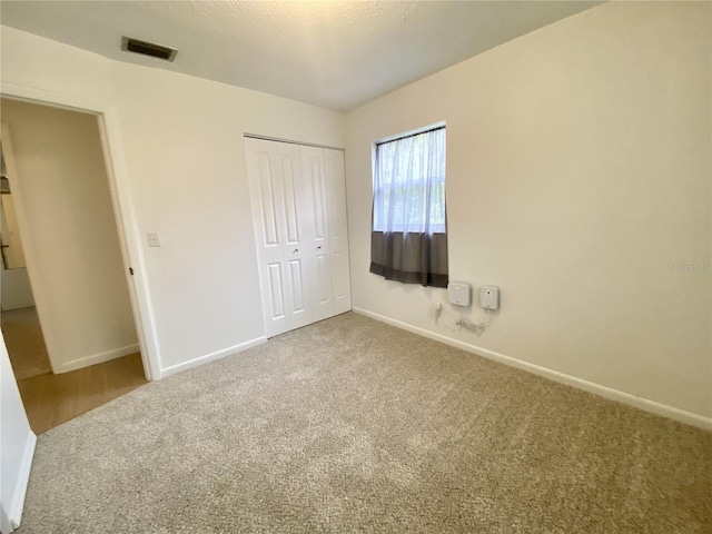 unfurnished bedroom with a closet, carpet floors, and a textured ceiling