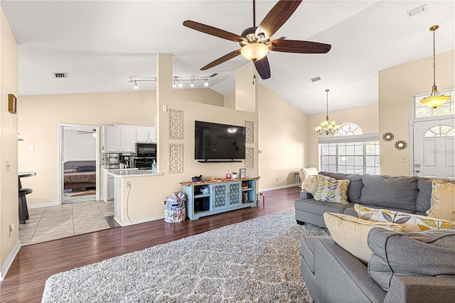 living room with rail lighting, a textured ceiling, ceiling fan with notable chandelier, high vaulted ceiling, and light hardwood / wood-style flooring