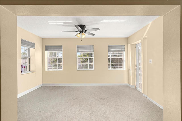 carpeted spare room featuring ceiling fan, a textured ceiling, and a wealth of natural light