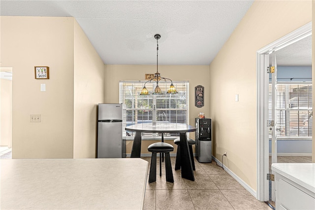 tiled dining room with a textured ceiling and a notable chandelier