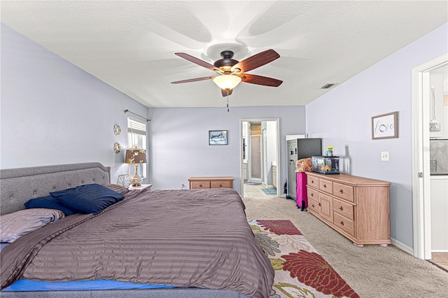 carpeted bedroom with a textured ceiling, ensuite bathroom, and ceiling fan