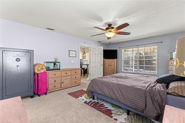 bedroom with a textured ceiling, ceiling fan, and light carpet