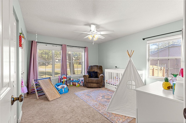 bedroom with ceiling fan, light colored carpet, a crib, and multiple windows